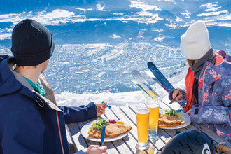 Zwei Sifahrer essen auf der Seegrube und genießen die Aussicht auf Innsbruck. Das Skigebiet Nordkette ist im SKI plus CITY Pass Stubai Innsbruck inkludiert.