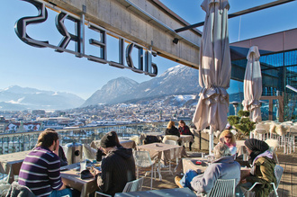 Menschen sitzen auf der Dachterrasse im Hotel Adler, mit Blick auf Innsbruck.