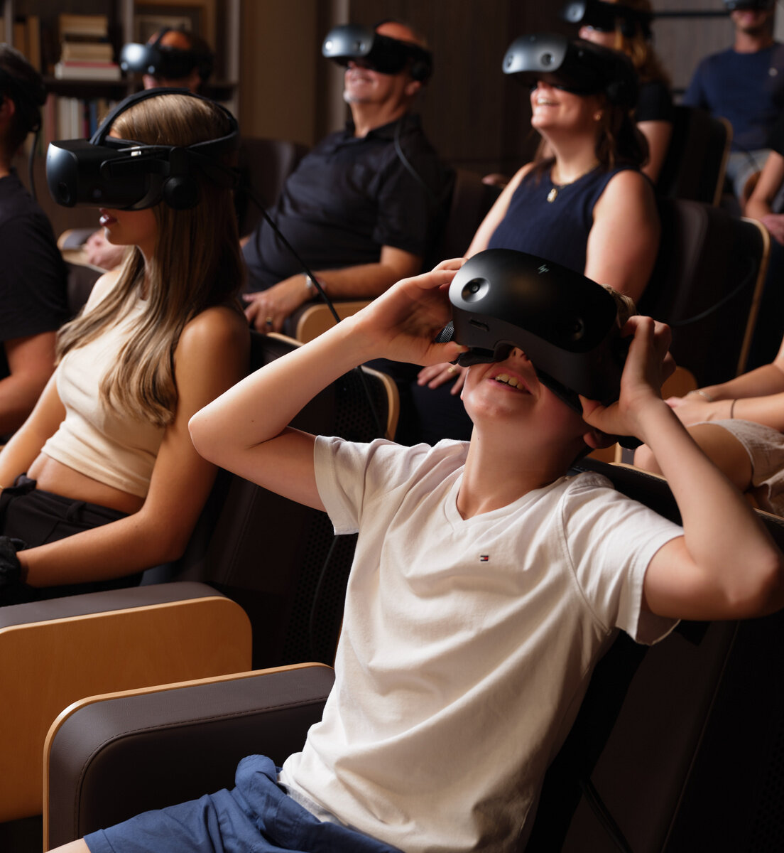 Personen sitzen mit VR-Brillen in Sesseln.
