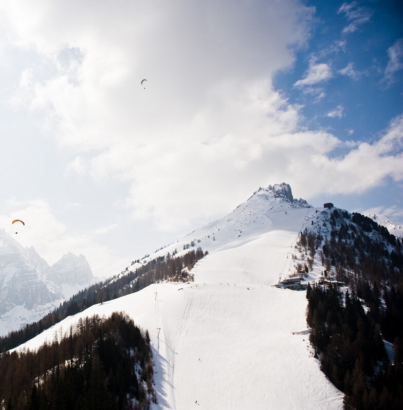Paragleiter fliegen über ein Skigebiet.