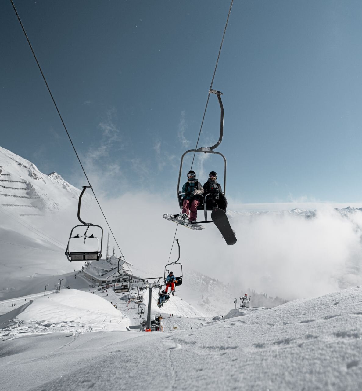 Zwei Snowboarder auf einem Sessellift.