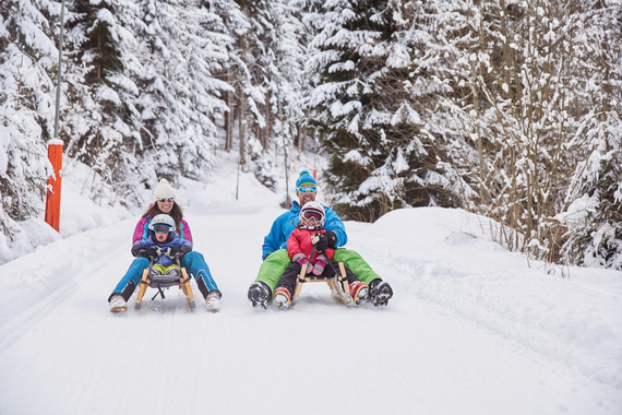 Eine Familie beim Rodeln. Das Skigebiet Rangger Köpfl ist im SKI plus CITY Pass Stubai Innsbruck inkludiert.