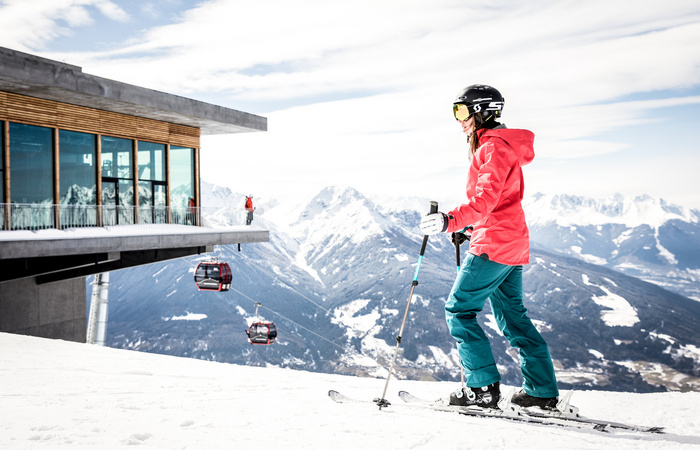 Eine Skifahrerin sieht der Gondel beim Abfahren zu. Das Skigebiet Patscherkofel ist im SKI plus CITY Pass Stubai Innsbruck inkludiert.